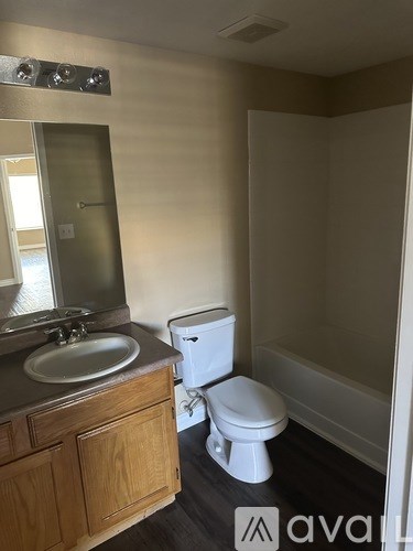 A bathroom with a toilet, sink, and mirror.