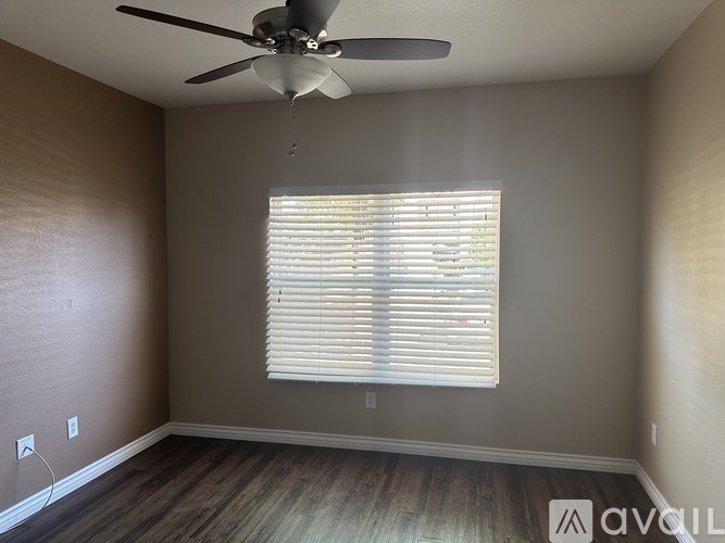 A room with a ceiling fan and a window with blinds.