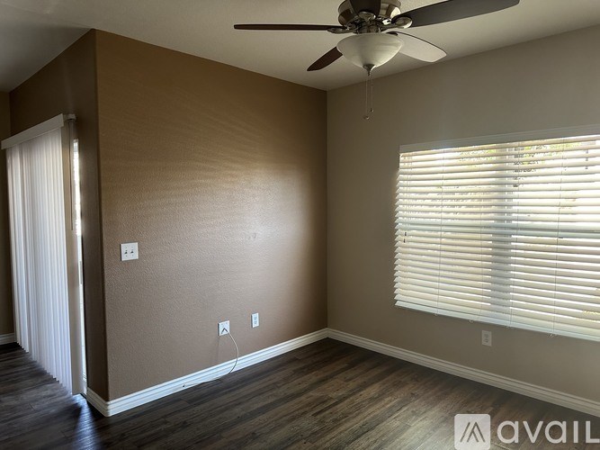 A room with a ceiling fan and a window with blinds.