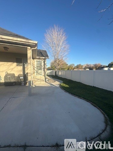 A concrete patio leads to a house with a white fence in the background.
