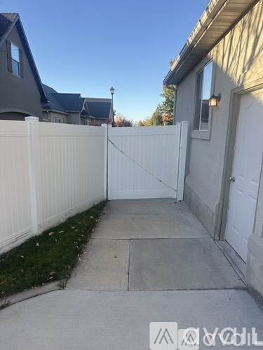 A white fence and a grey house with a white door.