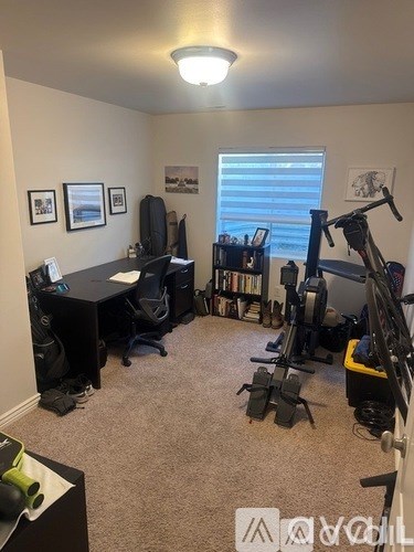 A room with a desk, chairs, and exercise equipment.