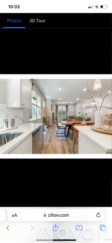 A 3D tour of a modern kitchen with white cabinets and a wooden floor.
