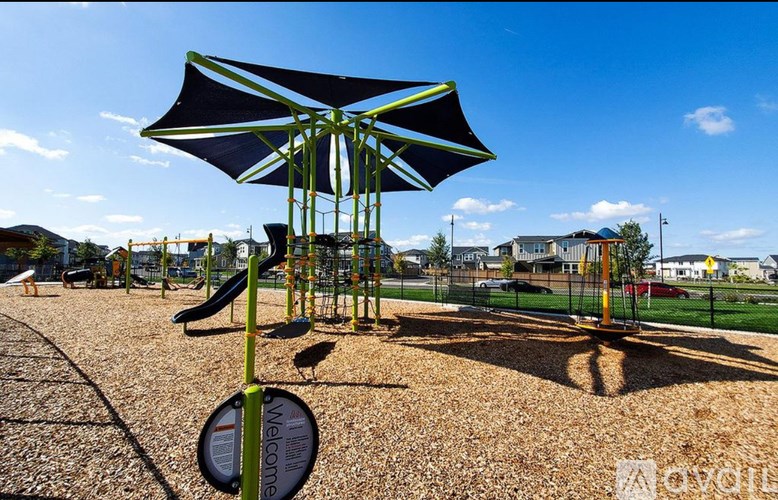 A playground with a swing set and a blue umbrella.