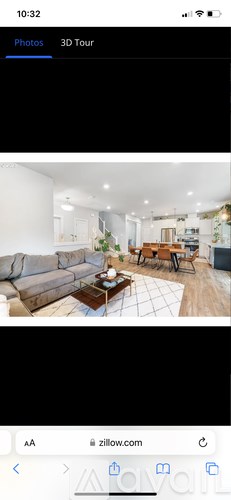 A 3D tour of a modern living room with a sofa, coffee table, and kitchen area.