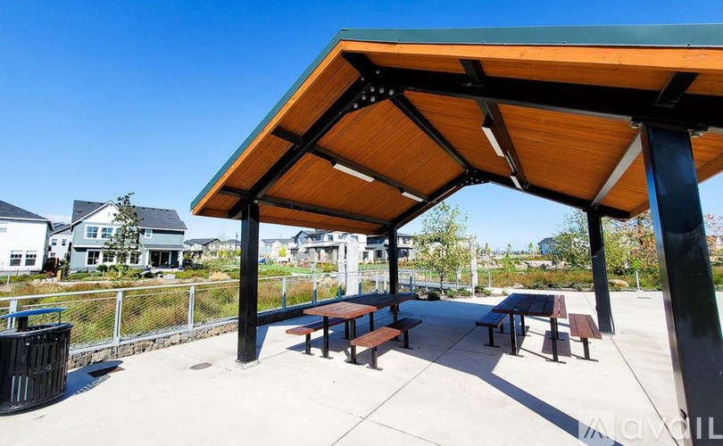 A covered picnic area with benches and a fence in the background.