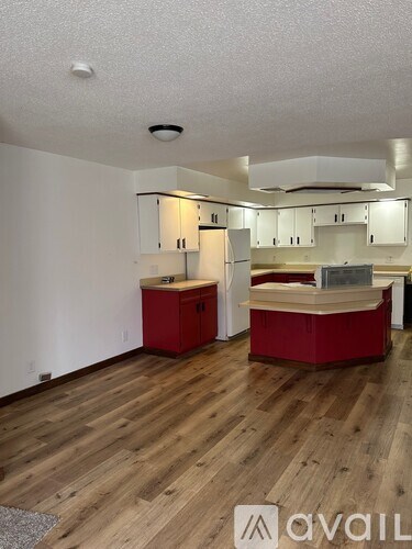 A kitchen with red cabinets and a wooden floor.