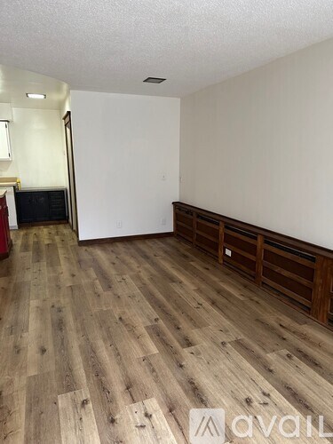 A room with wooden flooring and a white wall.