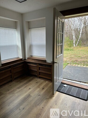 A room with wooden floors and a window with blinds.