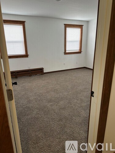 A carpeted room with a bench and two windows.