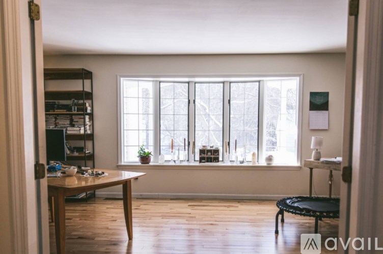 A room with a table, chairs, and a window with a view of trees outside.