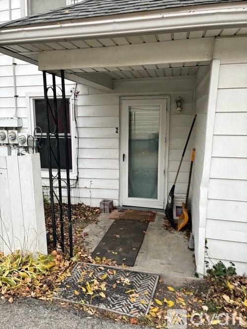 A white house with a black door and a black and white striped mat on the front step.
