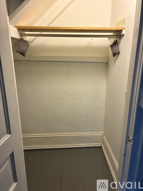A small, empty room with a door on the left and a shelf on the right.