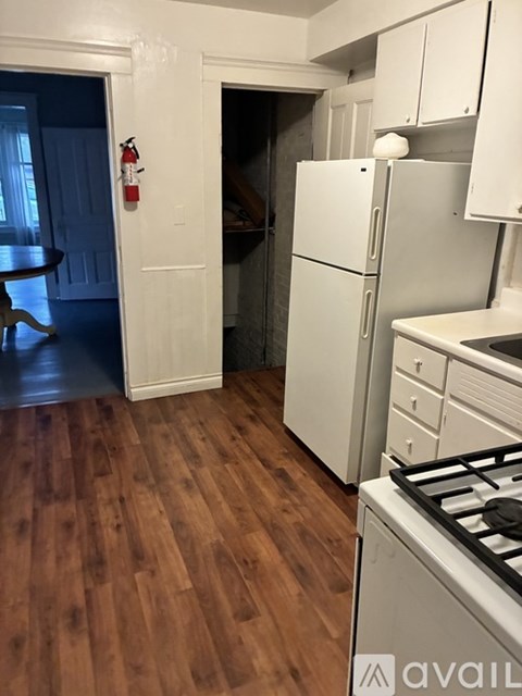 A kitchen with a white fridge and wooden floors.