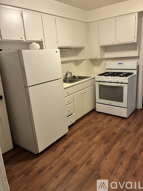 A kitchen with white appliances and wooden floors.