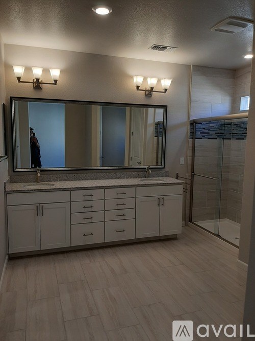 A bathroom with a large mirror and a vanity with drawers.