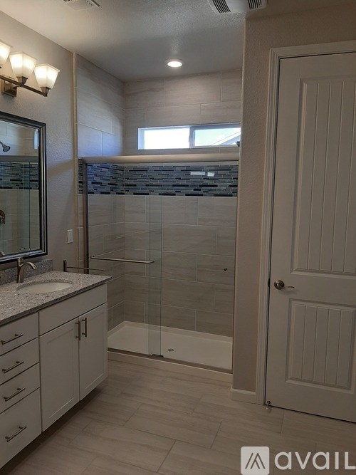 A bathroom with a sink, mirror, and shower.