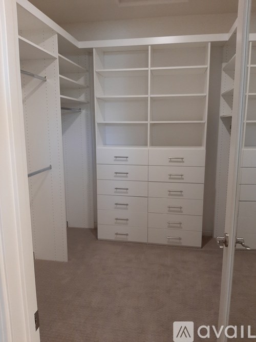 A white walk-in closet with drawers and shelves.