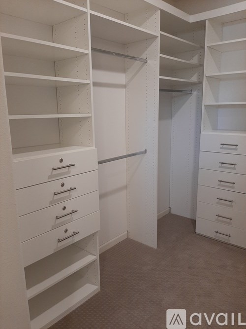 A white walk-in closet with drawers and shelves.