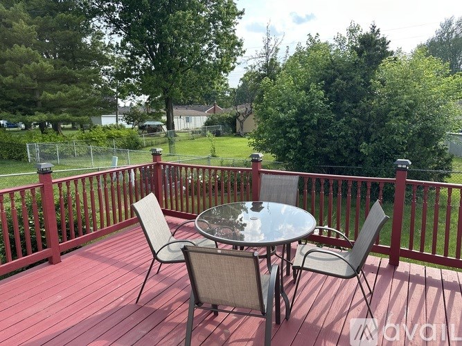 A table with four chairs is on a red deck.