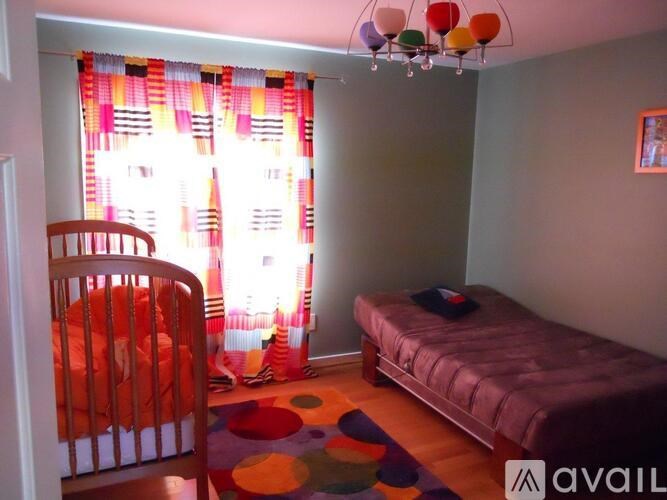 A room with a bed, a chair, and a colorful rug.