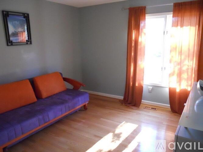 A living room with a purple couch and orange pillows.