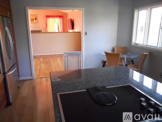 A kitchen with a refrigerator, a dining table with chairs, and a countertop with a cutting board and knives.