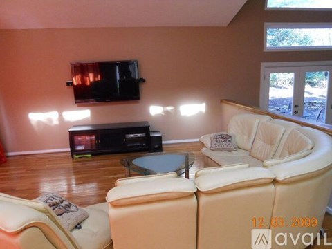 A living room with a white couch and a flat screen TV mounted on the wall.