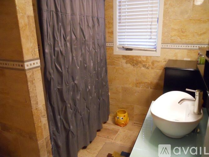A bathroom with a white sink, a shower curtain and a yellow cup.