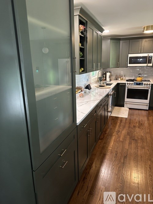 A modern kitchen with dark wood floors and stainless steel appliances.