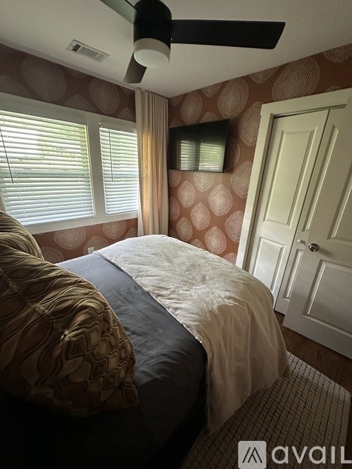 A bedroom with a bed, pillows, and a ceiling fan.