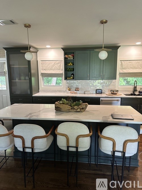 A kitchen with a marble countertop and white chairs.