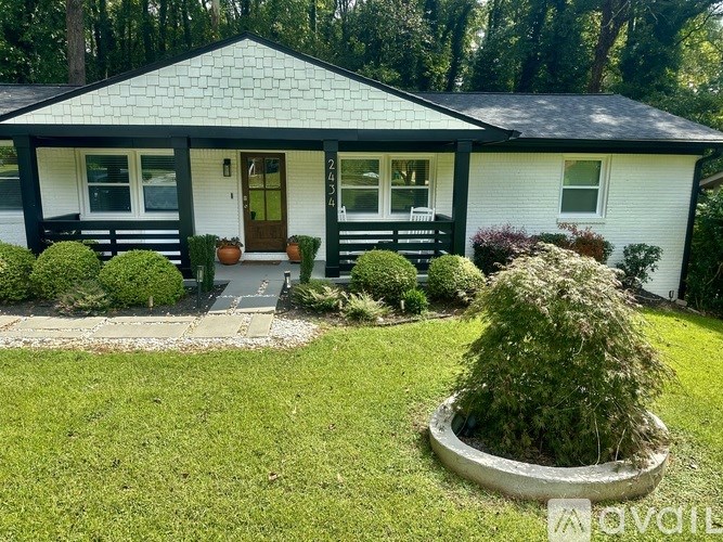 A small white house with a black roof and a front porch.