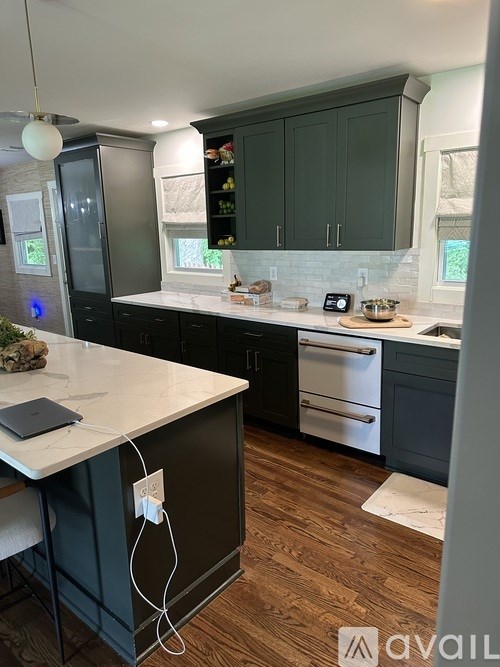 A kitchen with dark green cabinets and a white countertop.