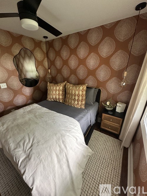 A bedroom with a bed, nightstand, and ceiling fan.