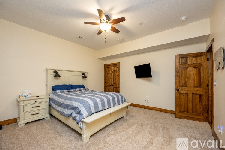 A bedroom with a bed, dresser, and ceiling fan.