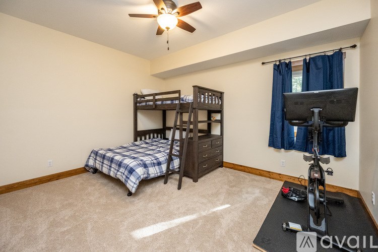 A room with a bunk bed, a desk with a computer, and a bicycle.