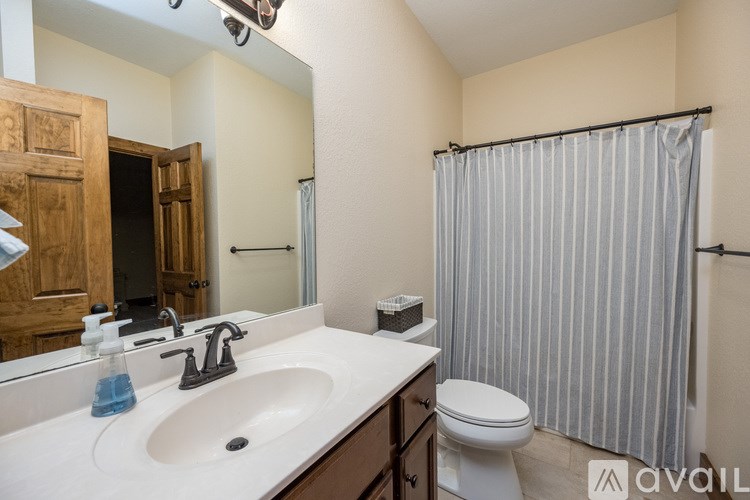A bathroom with a white sink, toilet, and striped shower curtain.