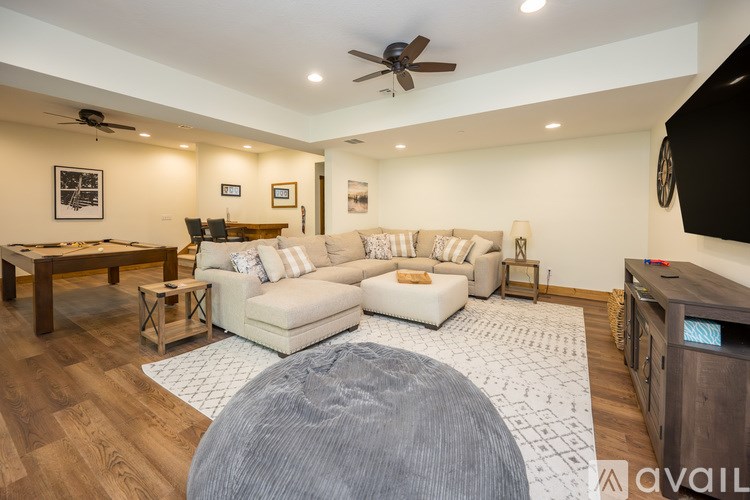 A living room with a white couch and a grey ottoman.
