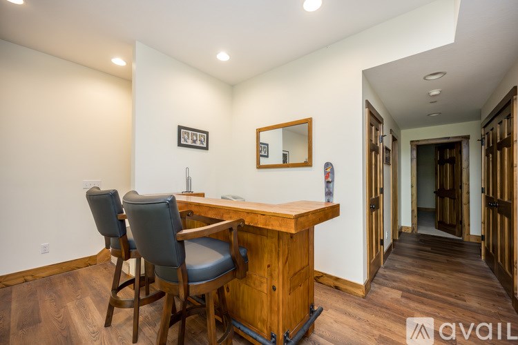 A wooden desk with two chairs and a mirror in a room.