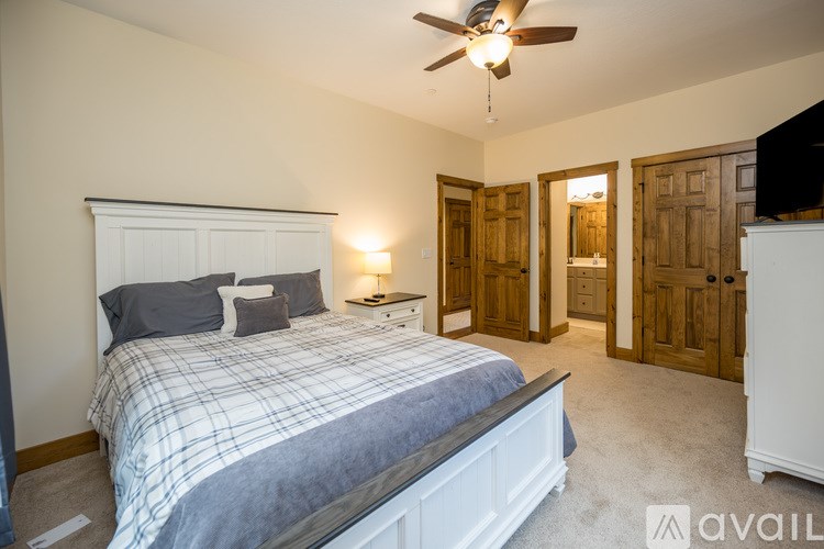 A bedroom with a bed, a ceiling fan, and a nightstand with a lamp.