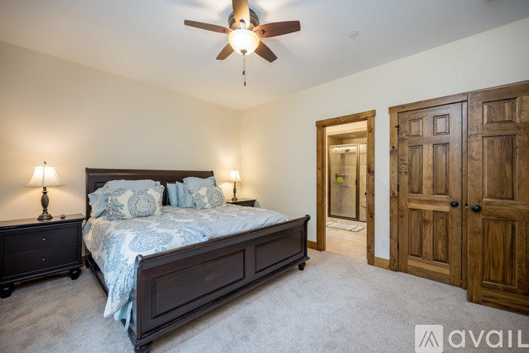 A bedroom with a bed, two lamps, and a ceiling fan.