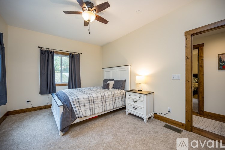 A bedroom with a bed, nightstand, and window.