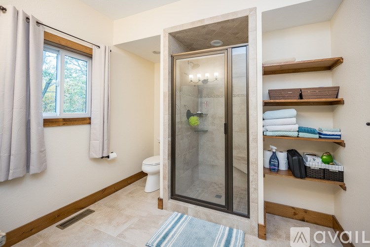 A bathroom with a glass shower door and a towel rack with towels.