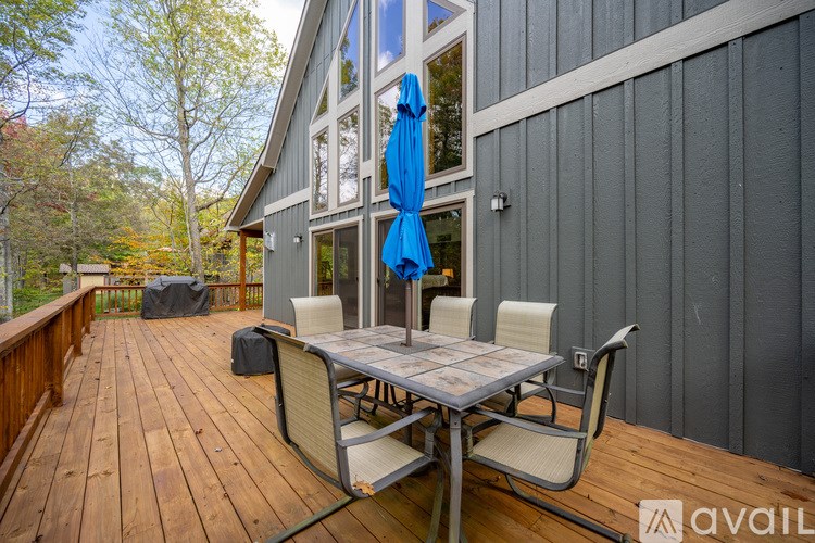 A wooden deck with a table and chairs and a blue umbrella.