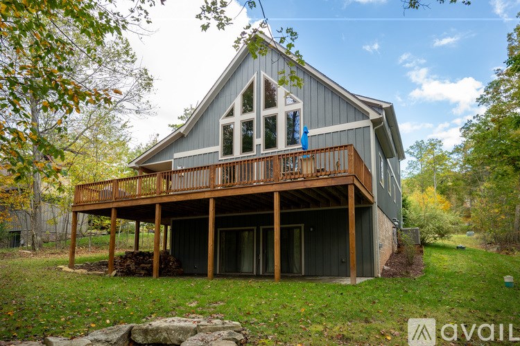 A house with a balcony is surrounded by trees and grass.