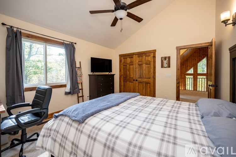A bedroom with a bed, chair, and a ceiling fan.