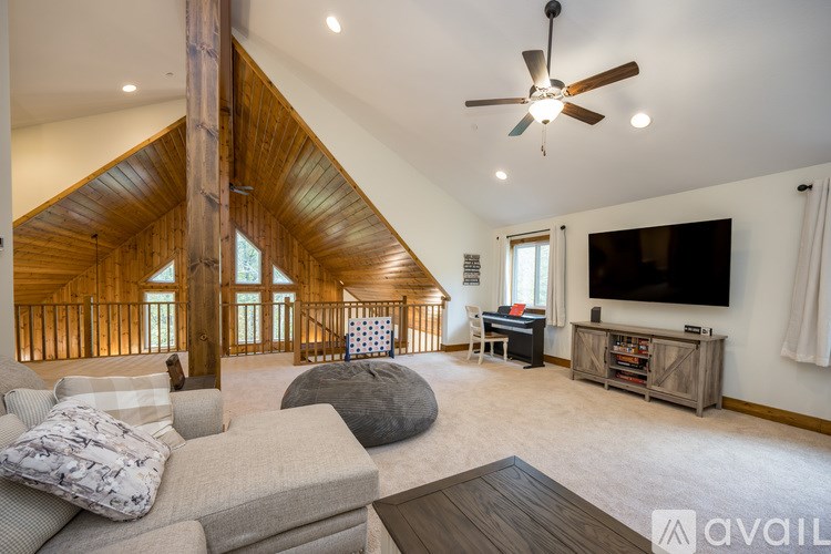 A spacious living room with a wooden ceiling and a large flat-screen TV mounted on the wall.