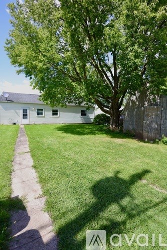 A house with a lawn and a tree in front of it.