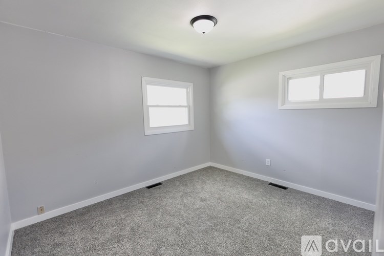 A room with a carpeted floor and two windows.